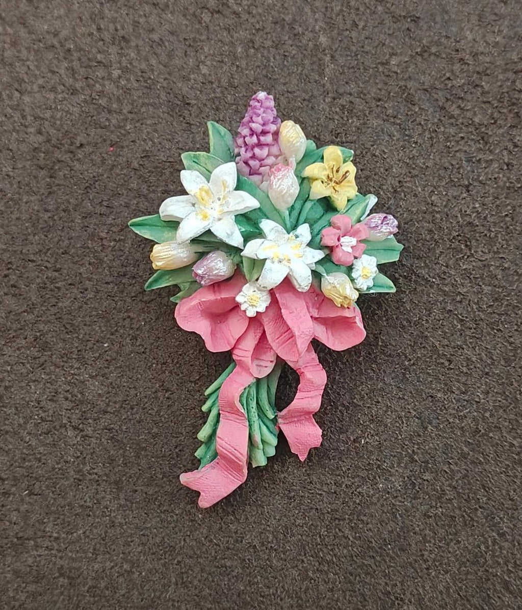 Floral resin brooch with pink ribbon tails and mixed white, purple, yellow blossoms