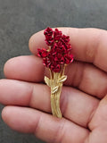 Gold tone rose bouquet brooch with red rose clusters, shown in a hand close-up