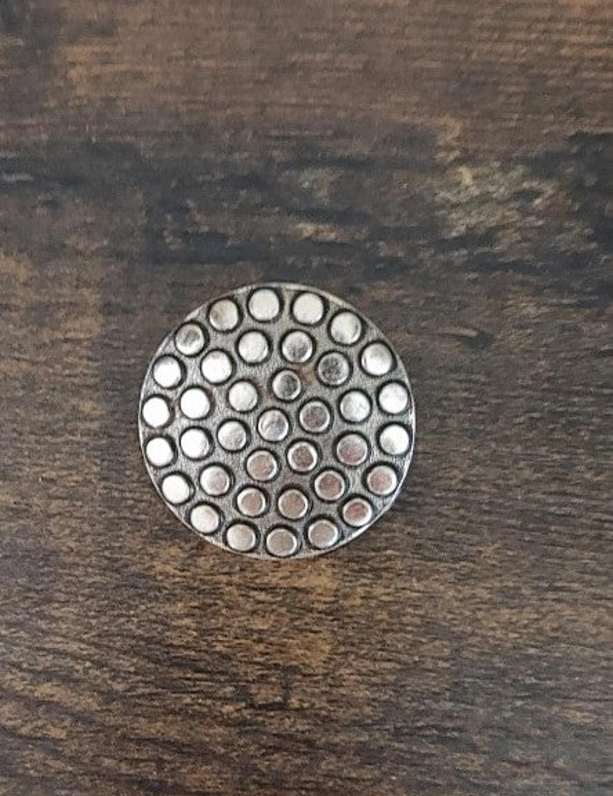 Round scarf clip face featuring a concentric dotted pattern in silver tone
