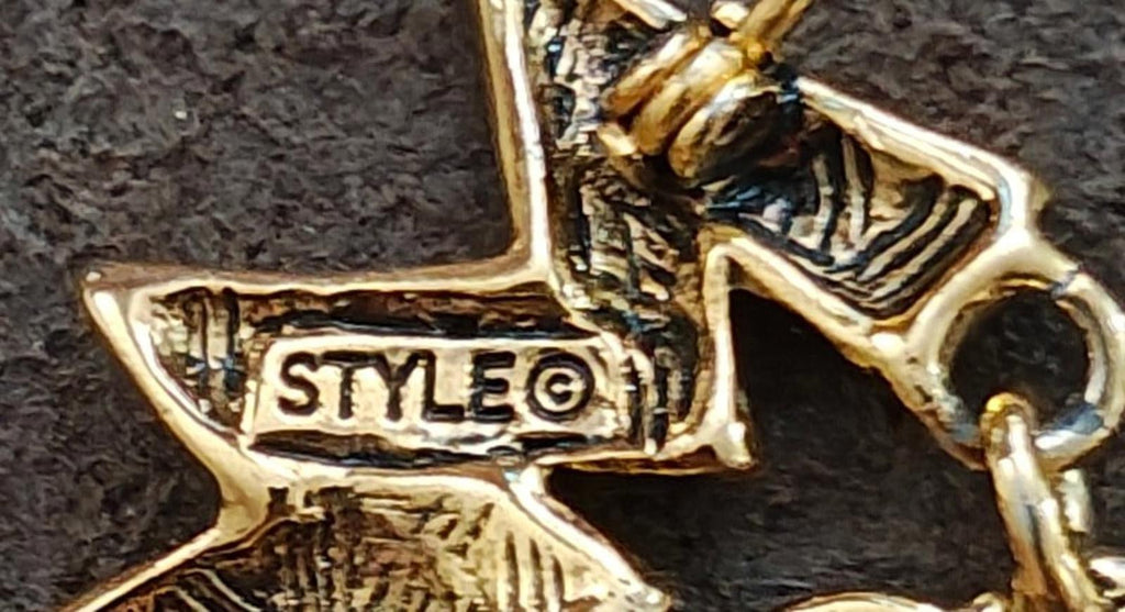 Gold-tone star charm clasp marked "STYLE@" on a brooch pin