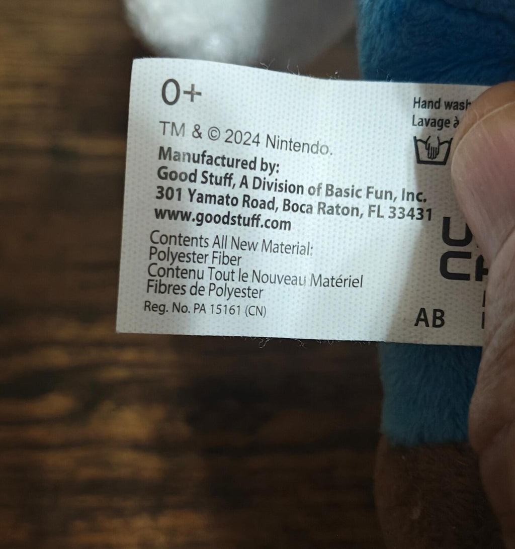 Fabric care label on Super Mario plush with “Hand wash” and “Made in” text
