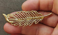 Gold-tone openwork leaf feather brooch with curved prong details