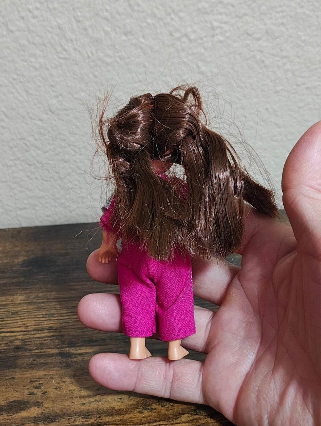 5-inch girl doll back view, long brown hair, pink romper with silver vest