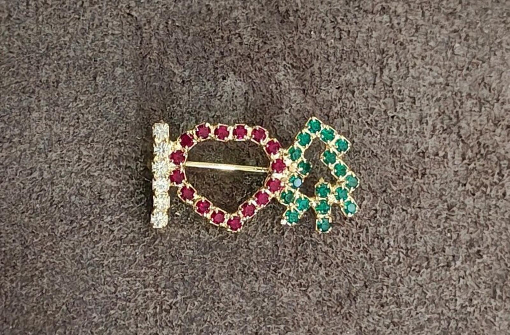Rhinestone brooch on dark cloth: red heart outline with green tree and clear vertical bar
