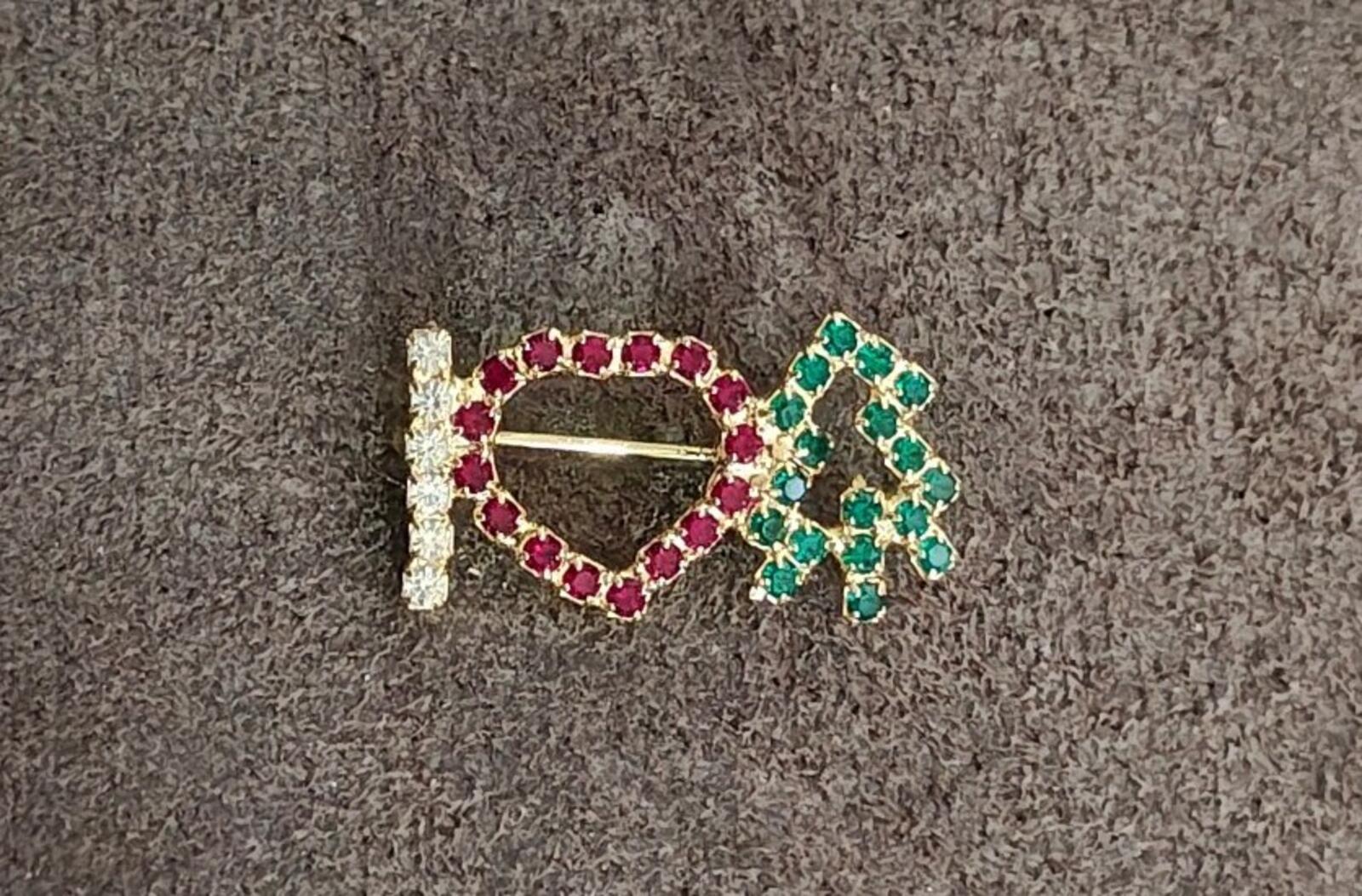 Rhinestone brooch on dark cloth: red heart outline with green tree and clear vertical bar