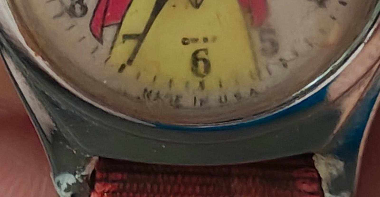 Close-up of vintage watch dial edge and red fabric strap stitching.