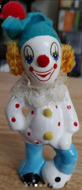 Vintage porcelain clown figurine with blue hat, white face, red nose, curly golden hair