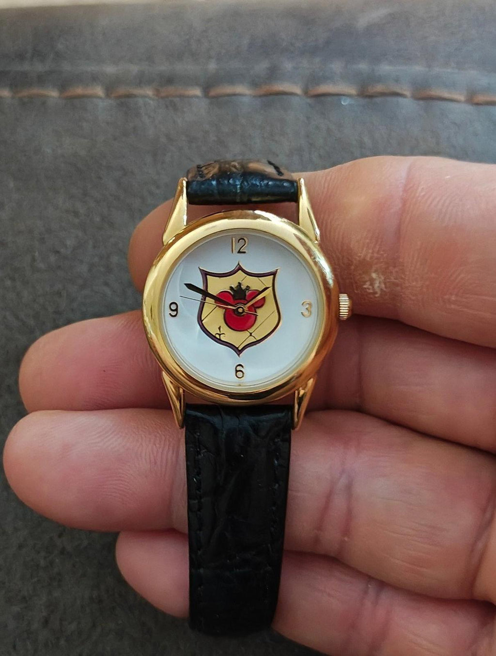 Quartz wristwatch with gold-tone case, black leather strap, and Mickey-style dial.