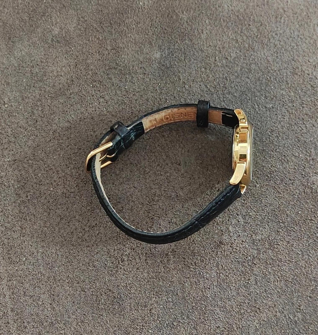 Black leather wristwatch strap with gold-tone case and side view.