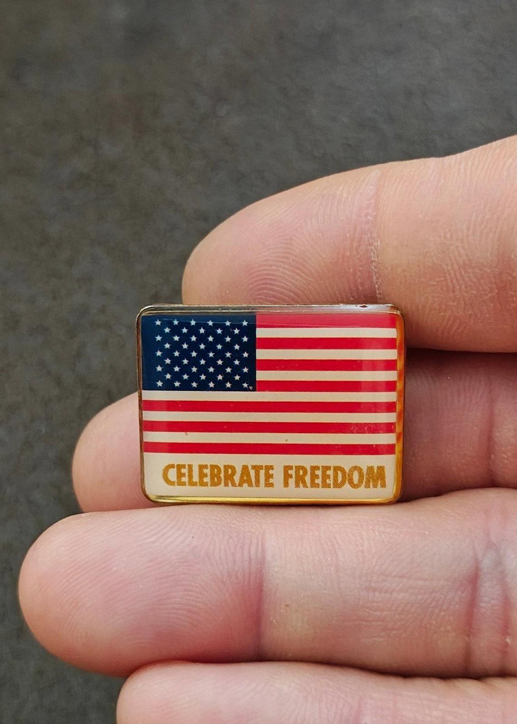 Small rectangular flag pin in gold-tone frame with “CELEBRATE FREEDOM”
