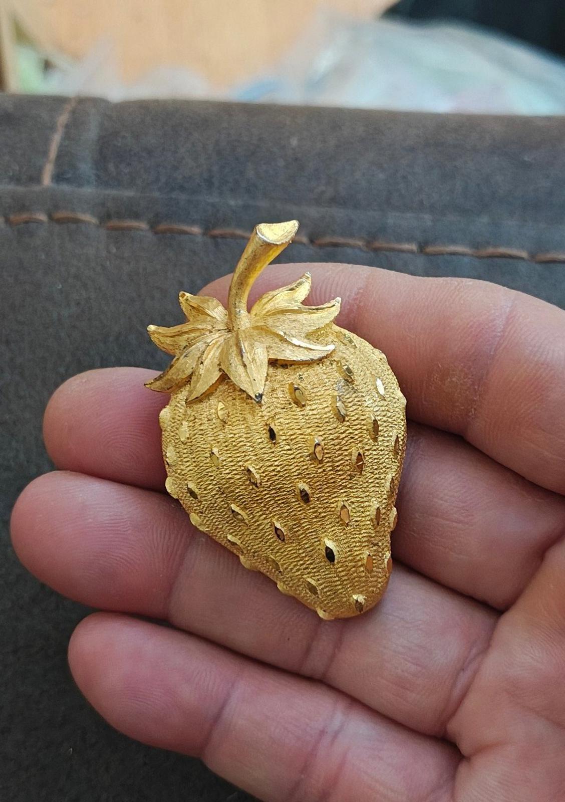 Gold tone strawberry brooch pin with stem and layered leaves, textured seed dots.