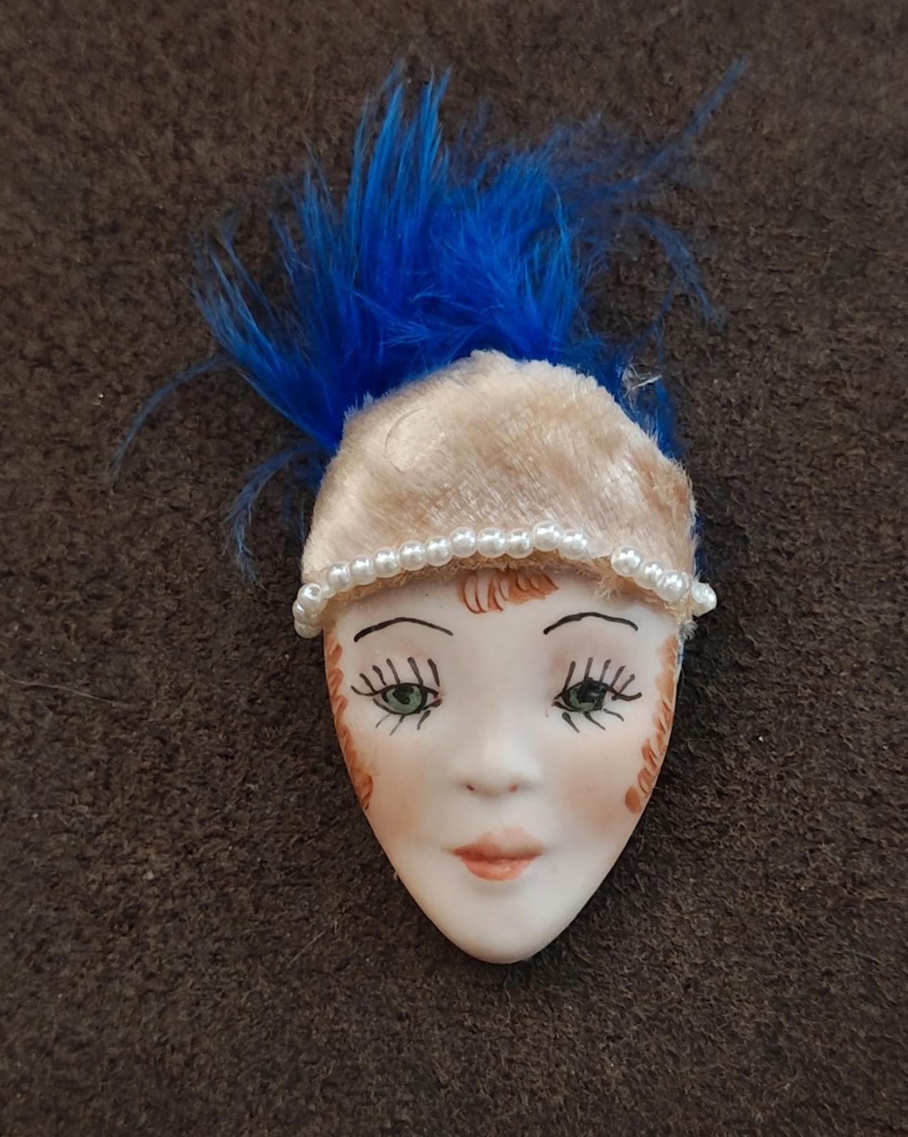 Doll face pin brooch with blue feather and cream headband with pearl beads