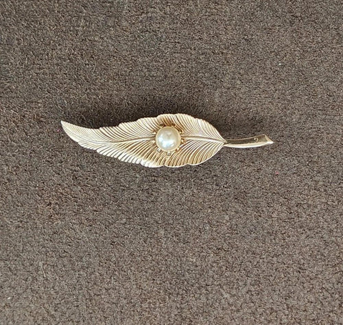Gold-tone leaf brooch with textured feather-like design and faux pearl center