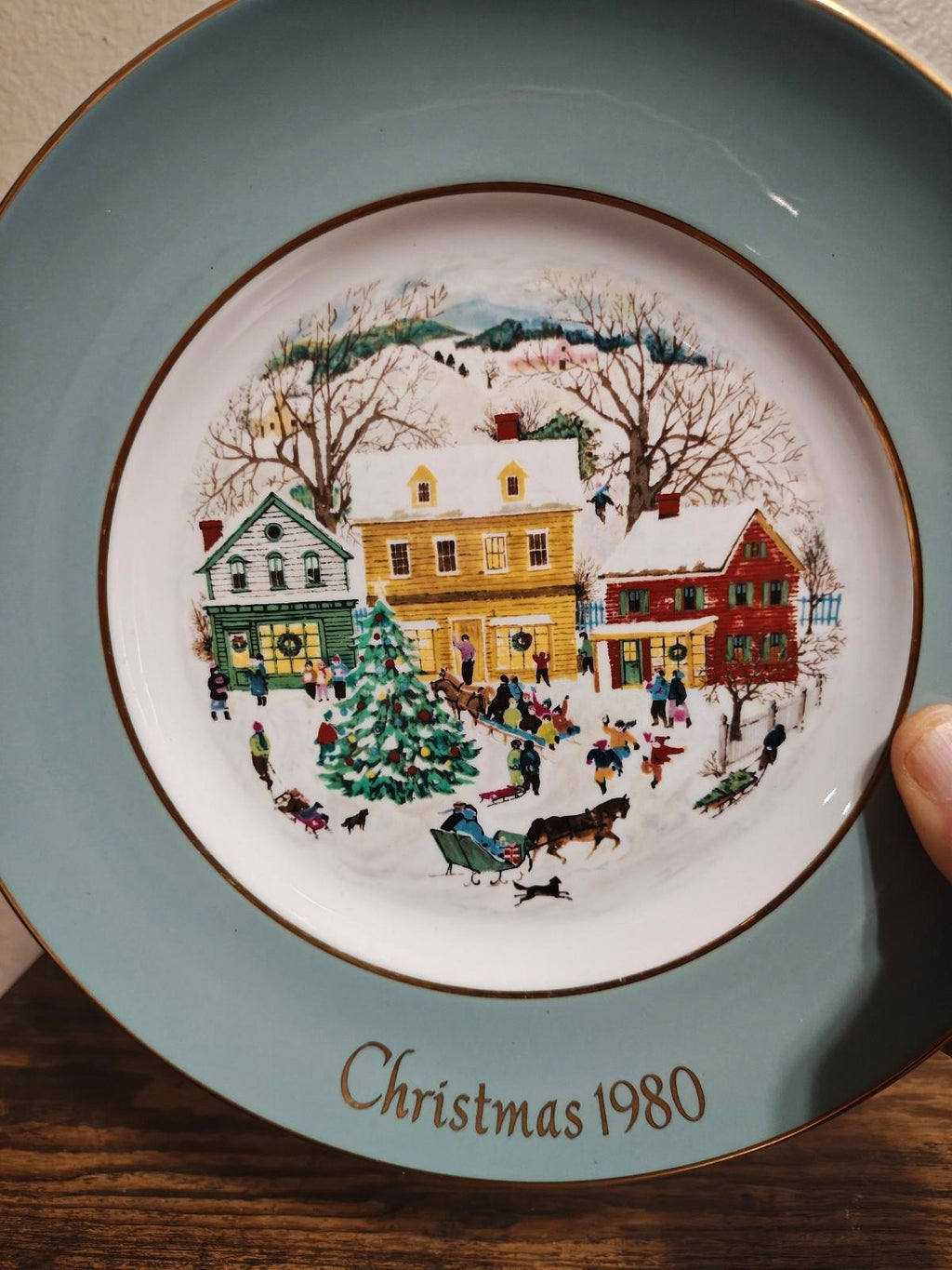 Light blue porcelain Christmas plate with 1980 scene, gold border, and gold-rim edge