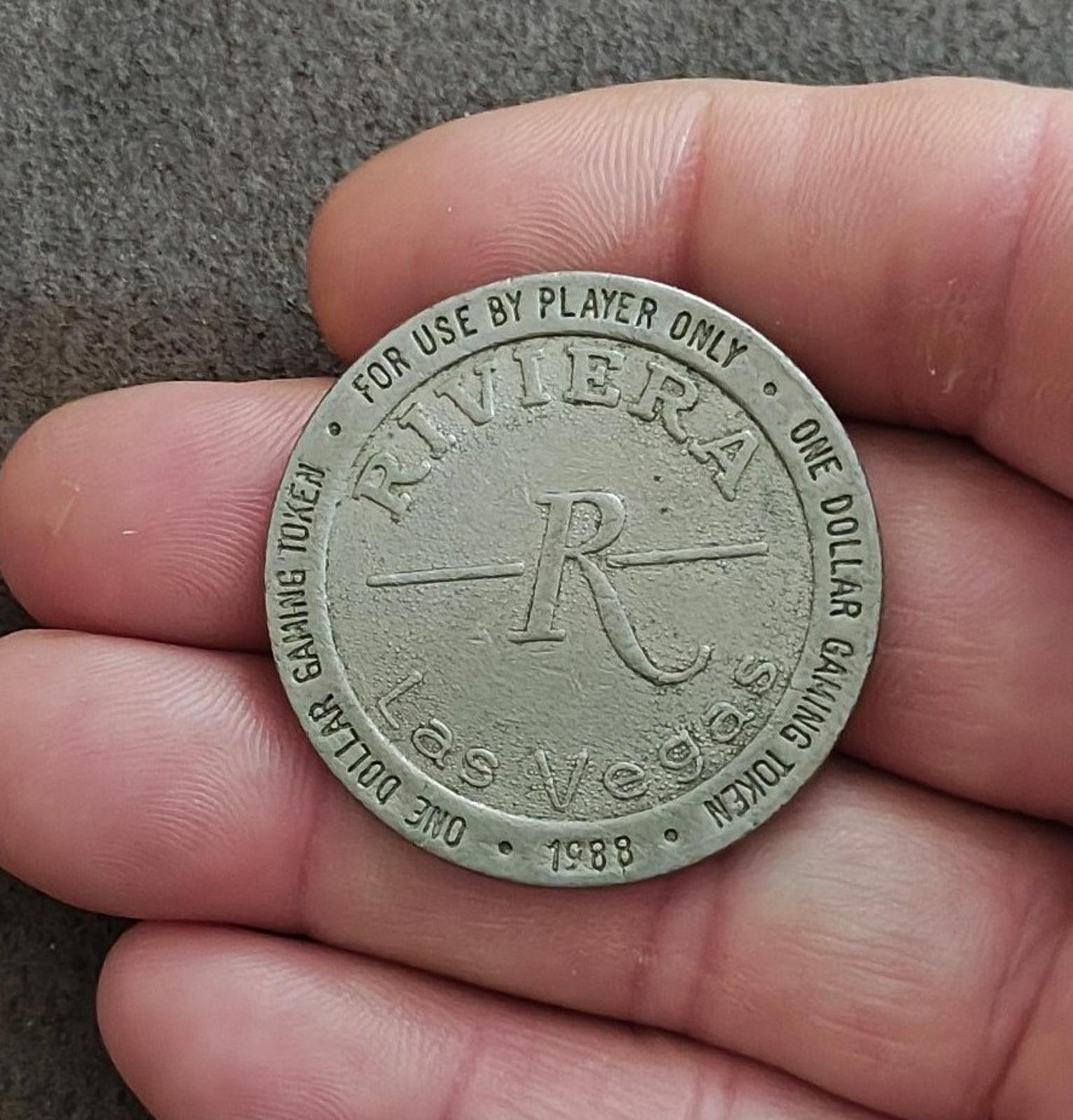 Silver one-dollar gaming token held in hand with Riviera logo and 1988 date