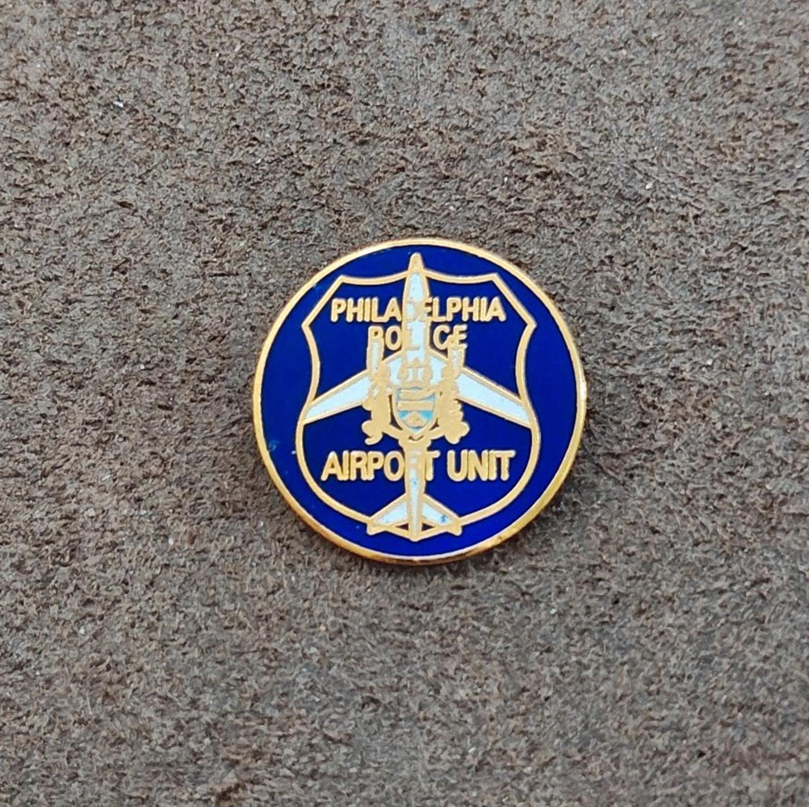 Round blue and gold Philadelphia Police Airport Unit pin on textured background