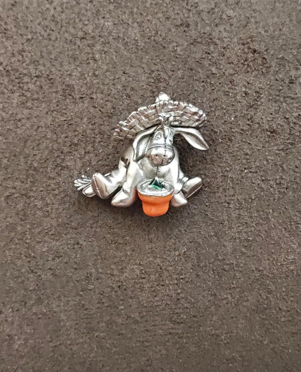 Eeyore pewter enamel pin showing silver figure with orange base and green center