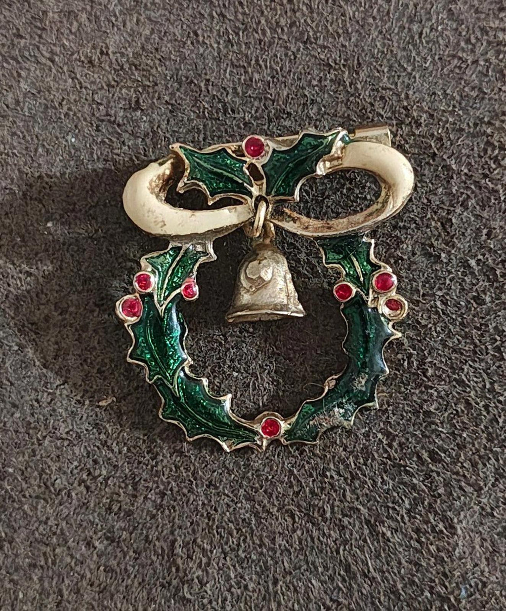 Gold-tone wreath brooch with green enamel leaves, red berries, and central hanging bell