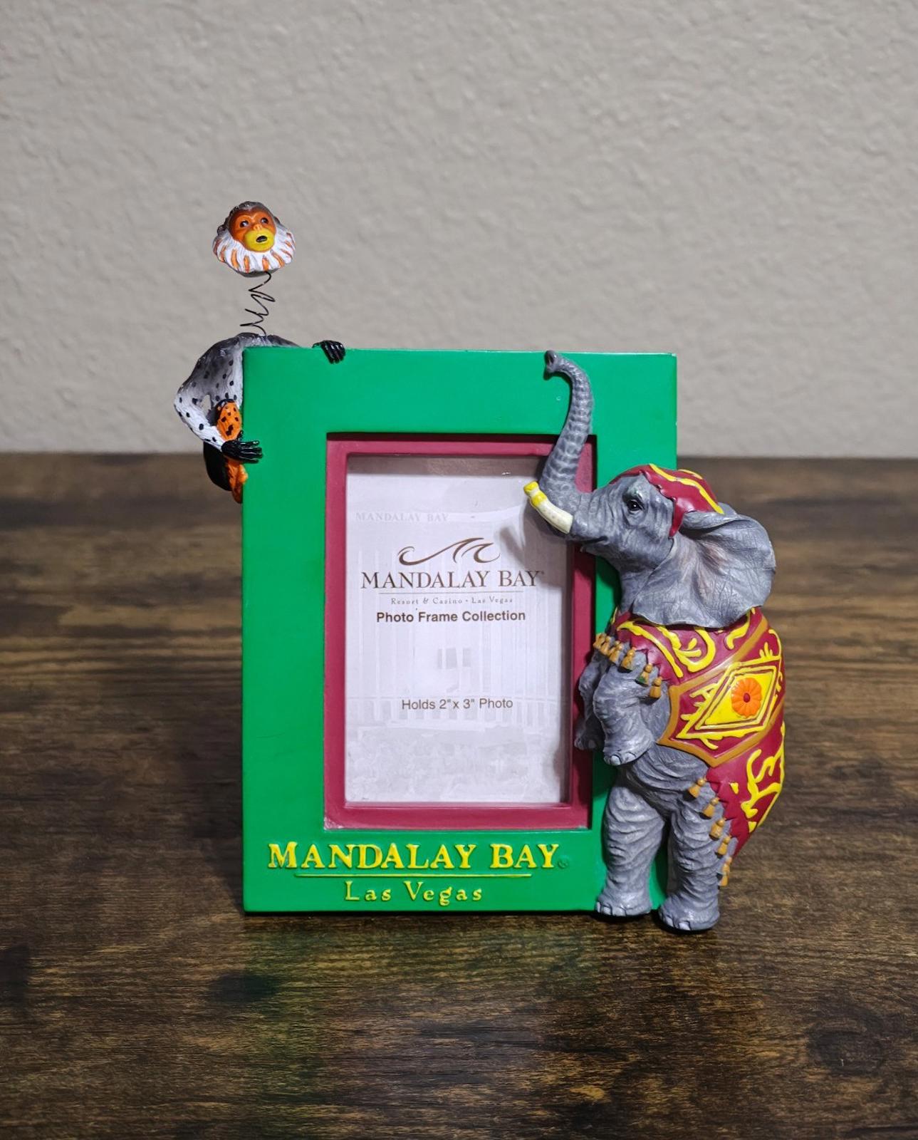 Green souvenir photo frame with elephant and monkey figurines, standing on base