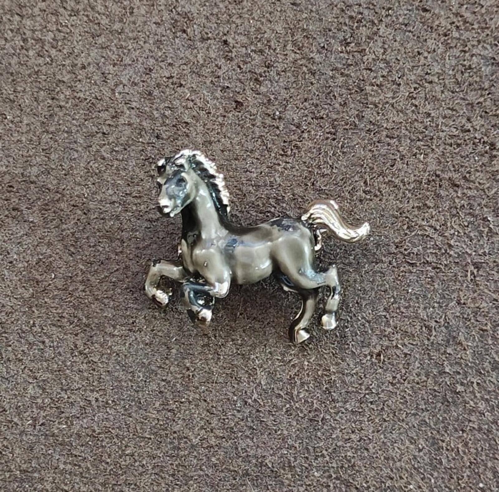 Small prancing horse brooch with silver-tone frame and dark enamel accents