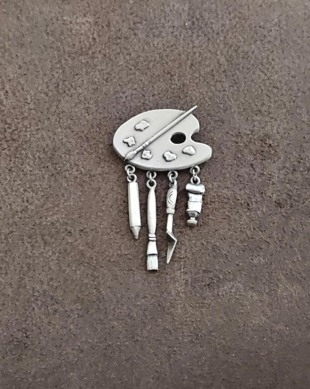 Silver-toned palette brooch with five tool dangles and round cutout hole, pin