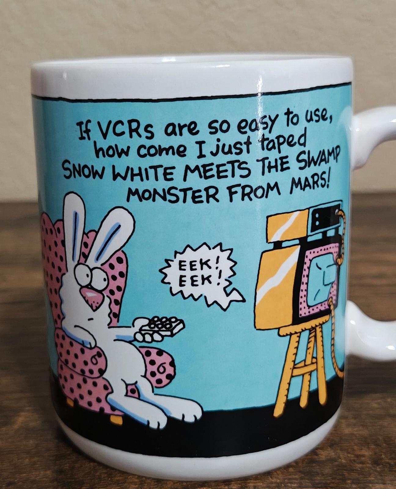 Blue ceramic mug close-up: VCR joke text, rabbits, and retro TV monster figure