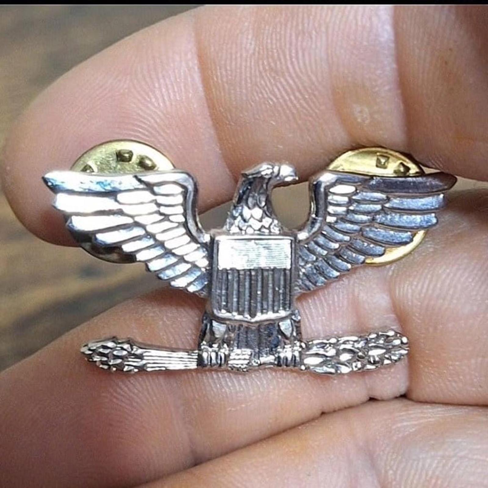 Eagle rank pin with silver wings and central shield, gold-toned round insets on ends