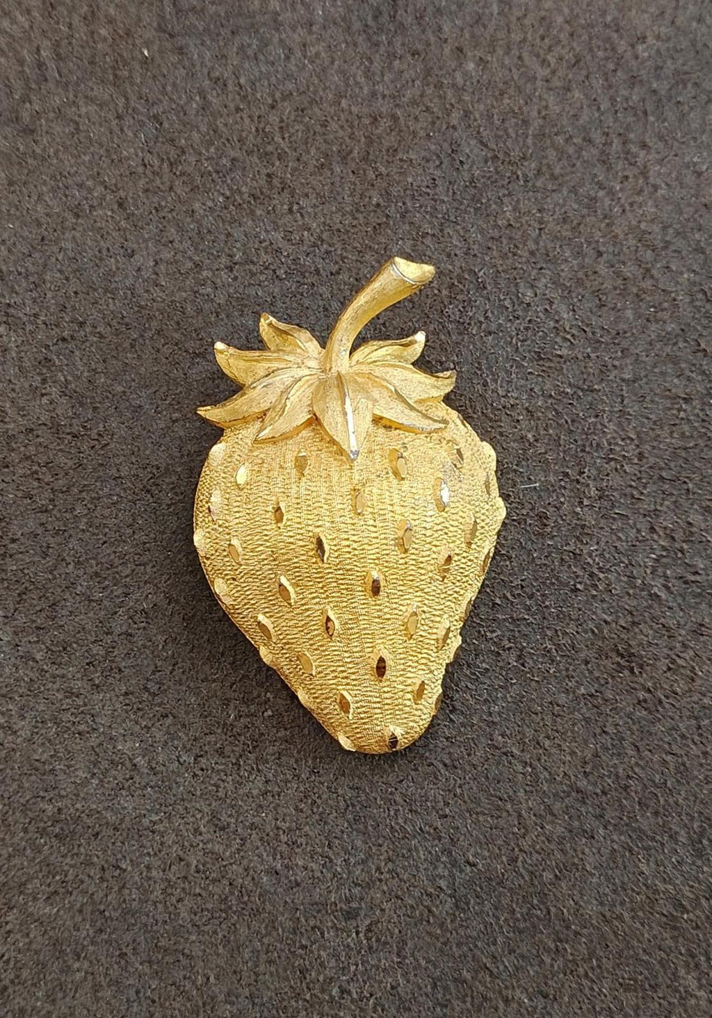 Gold tone strawberry brooch pin with leaf top and dotted seed texture.