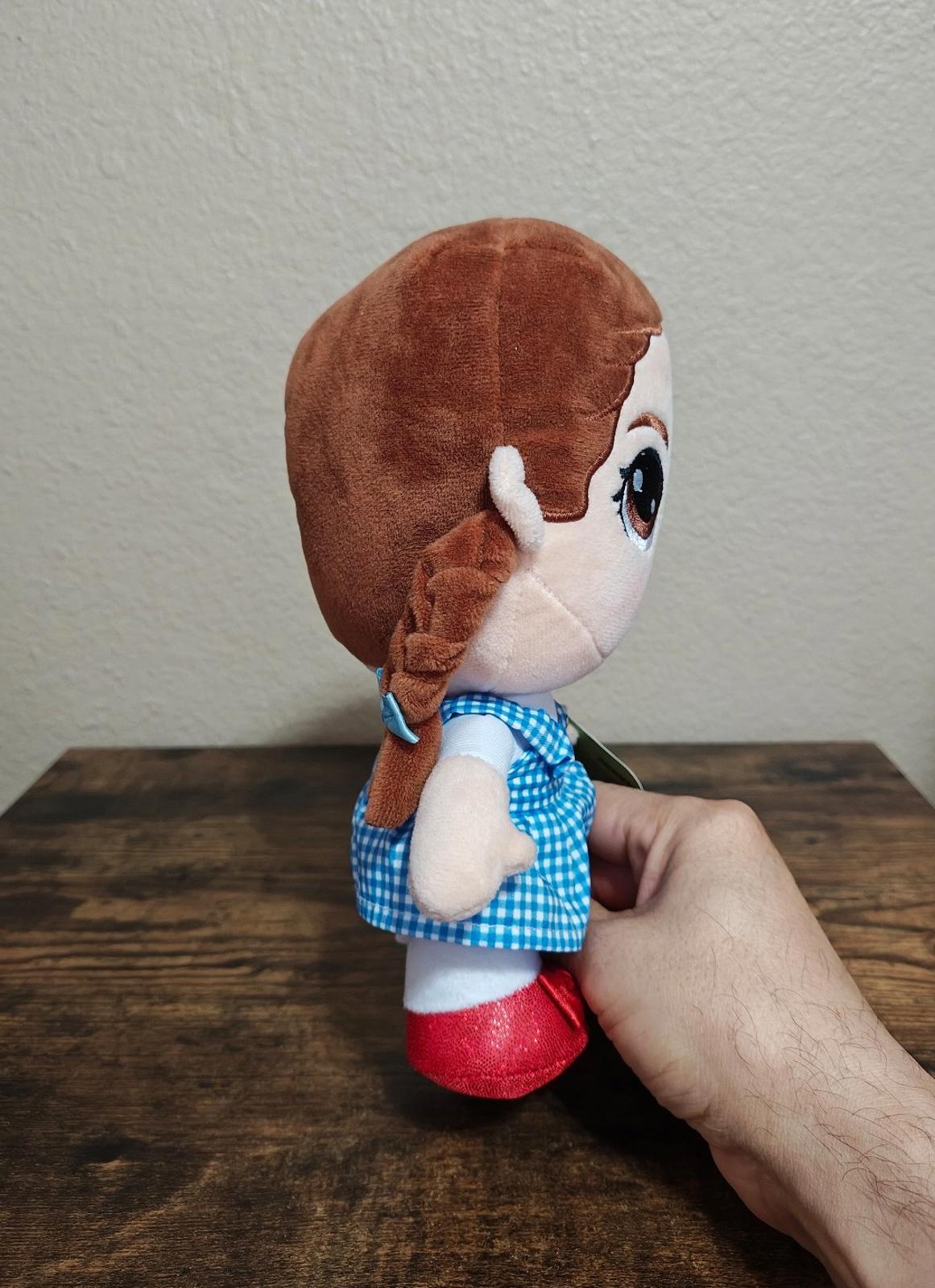 Dorothy-style plush doll profile view, blue gingham dress and red shoes, green hangtag
