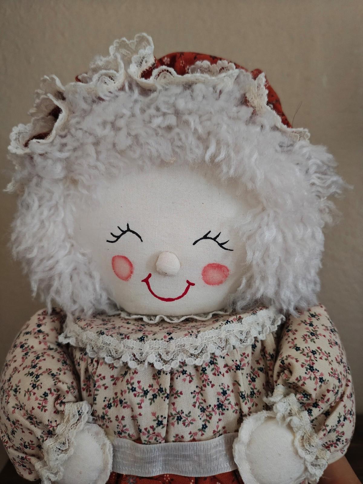 Handmade cloth doll canister with embroidered smile and fluffy white bonnet, front view.