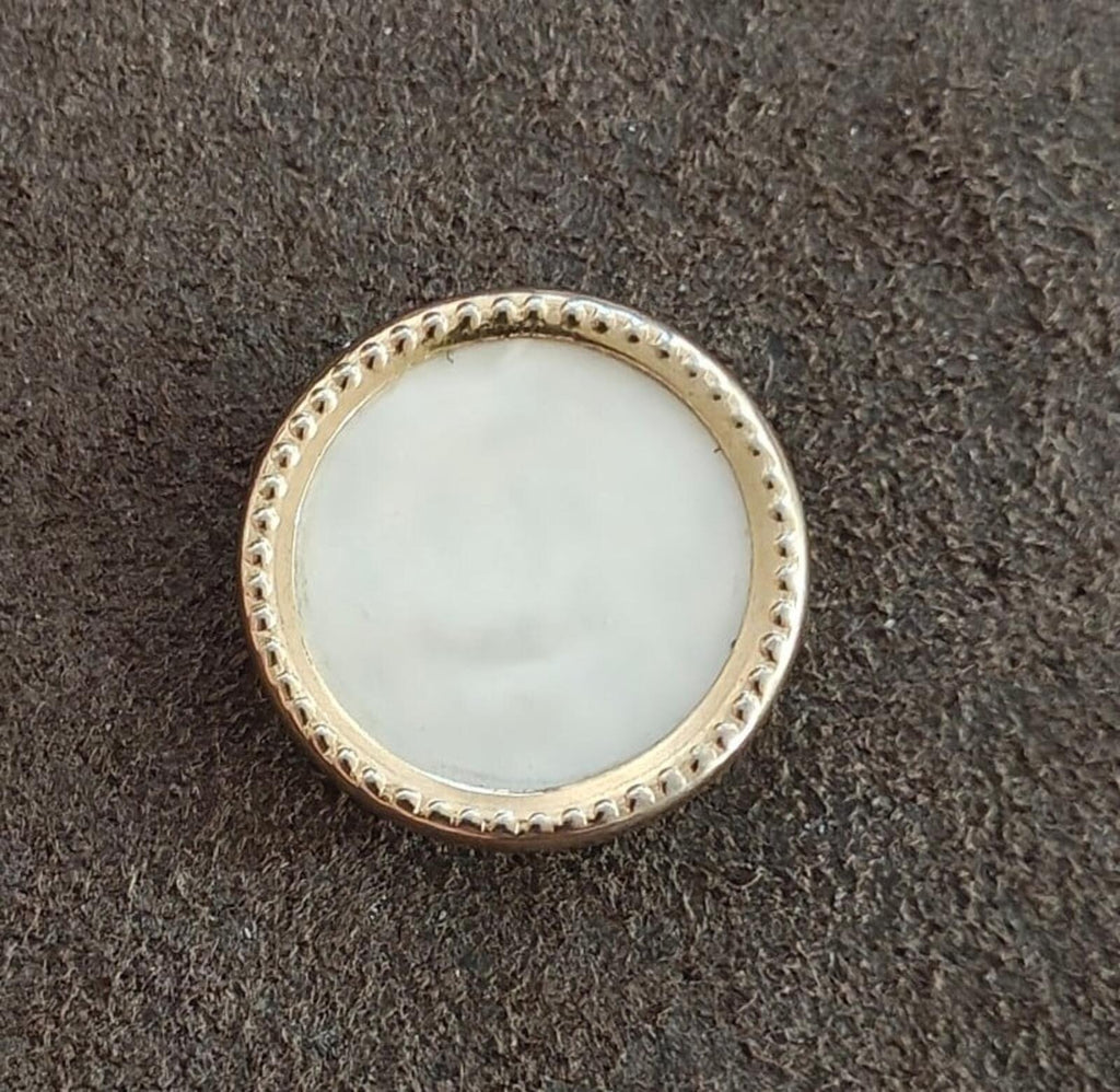 Round gold-tone mother-of-pearl brooch with textured bezel border