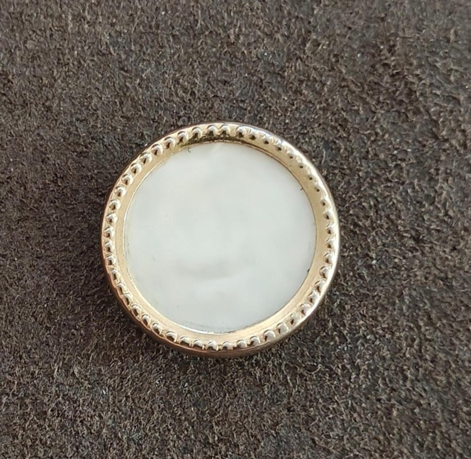 Round gold-tone mother-of-pearl brooch with textured bezel border