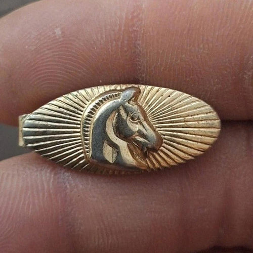 Gold-tone oval tie bar clip with horse profile relief and sunburst border