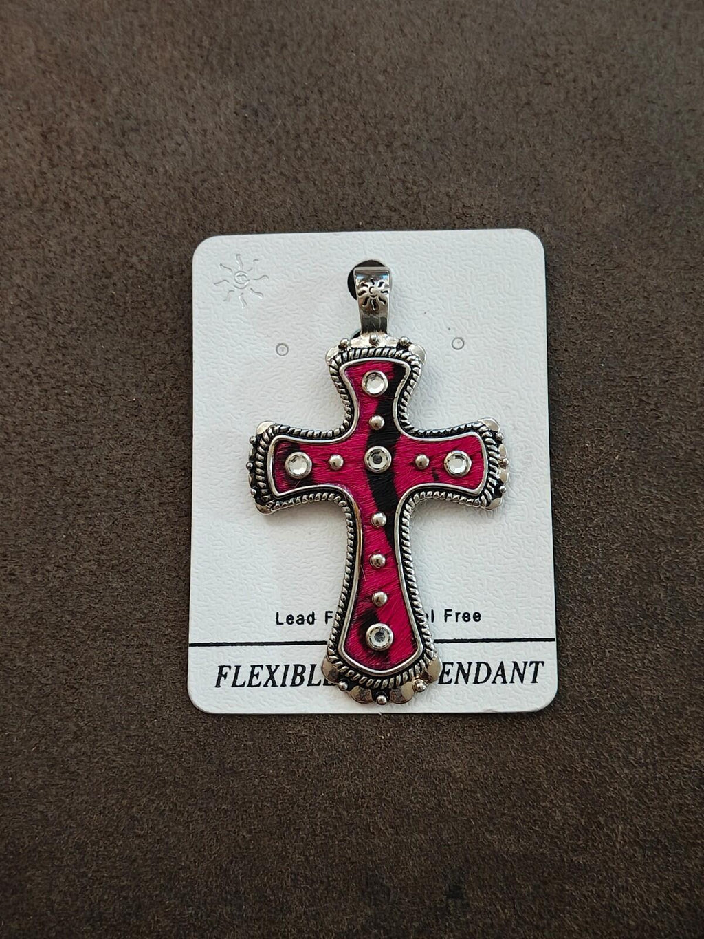 Pink cross pendant with rhinestone studs and ornate silver edging, hanging bail on card