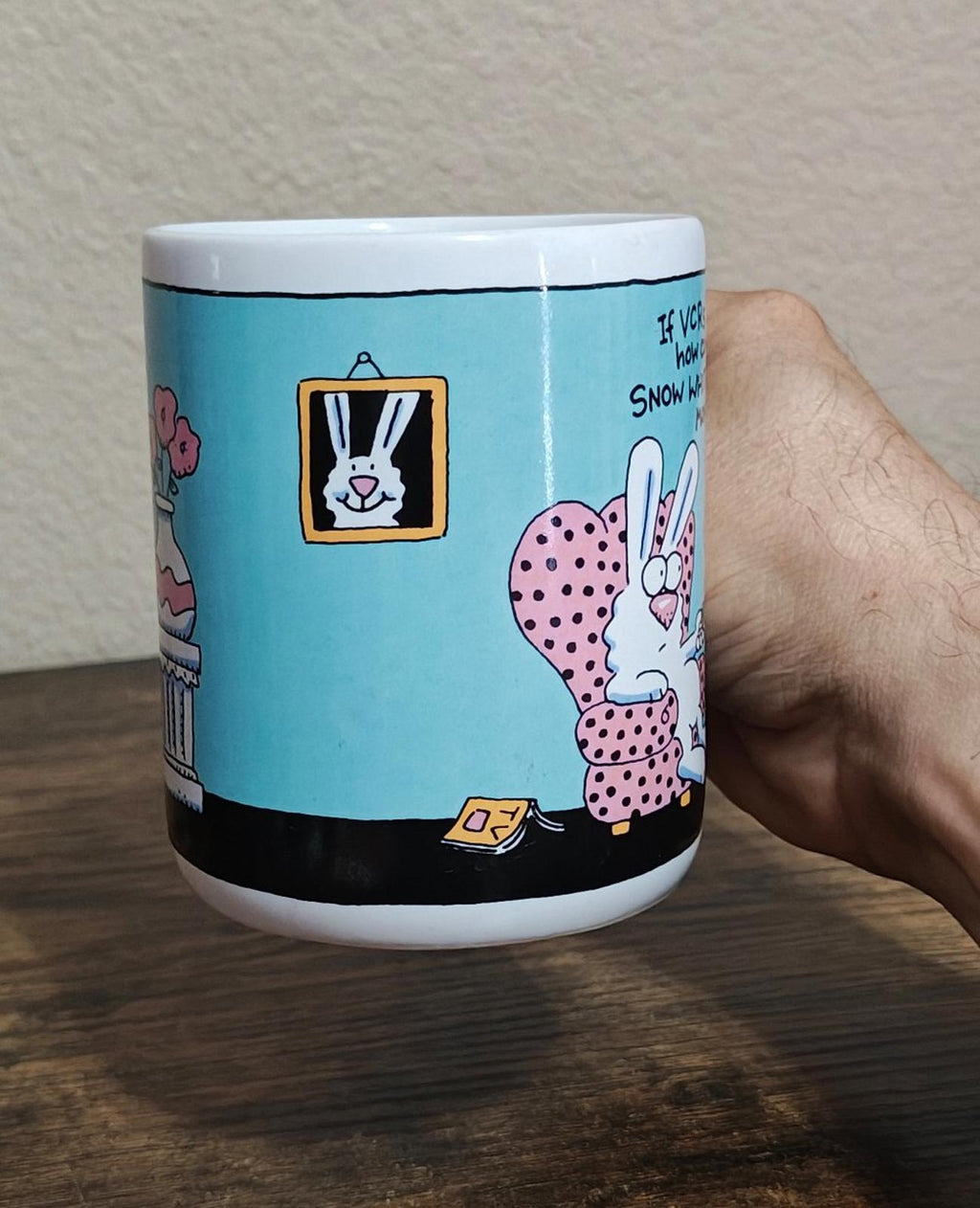 Blue ceramic mug side view with cartoon rabbit character near framed art
