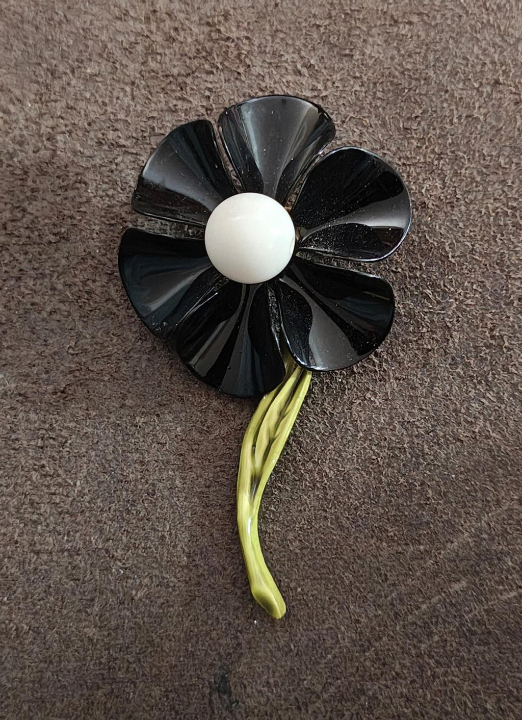 Black enamel flower pin with white center and green curved stem detail