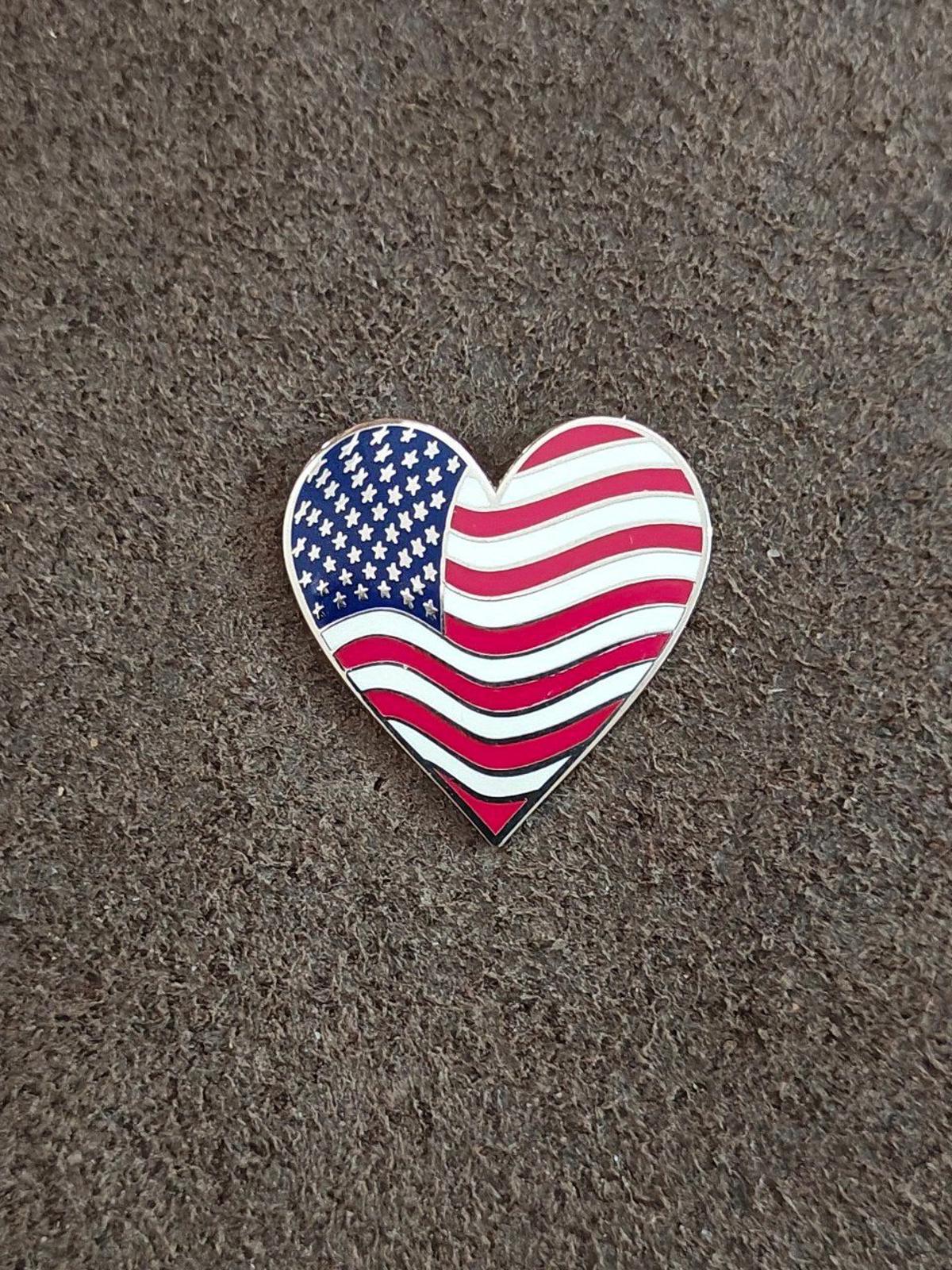 Small heart-shaped American flag enamel pin with blue stars and red/white wavy stripes