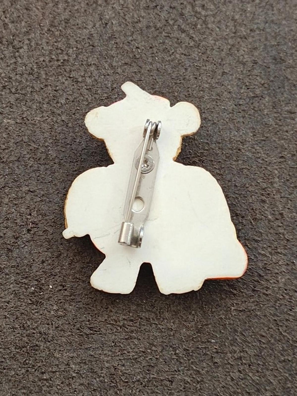 Teddy bear-shaped brooch backing with metal pin and clasp on white base