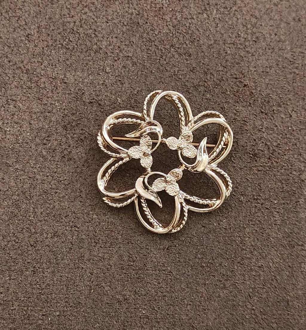 Gold-tone flower brooch with five curled petals and small textured accents