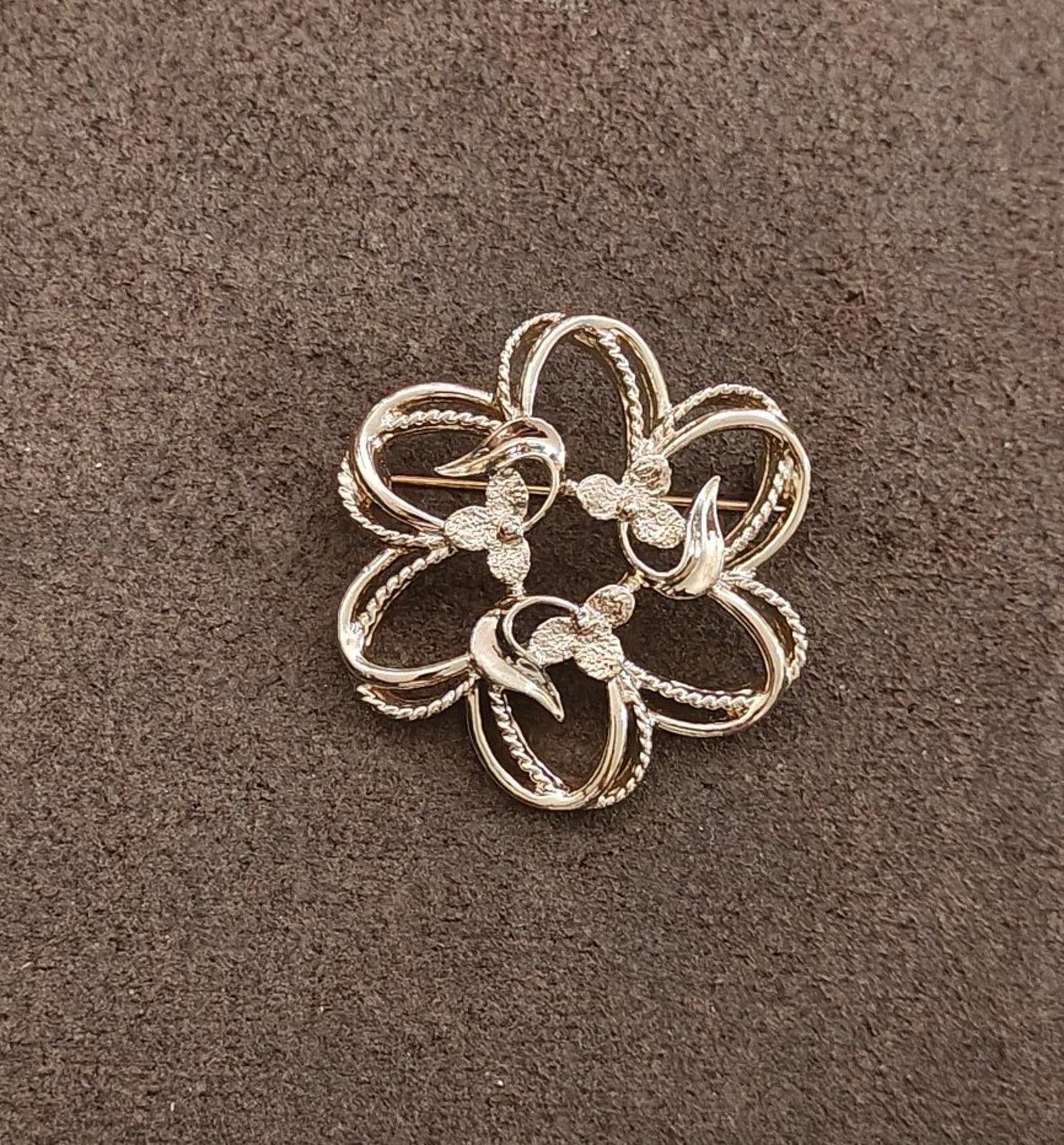 Gold-tone flower brooch with five curled petals and small textured accents