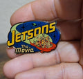 Jetsons The Movie enamel magnet, blue oval with yellow logo and cartoon saucer scene