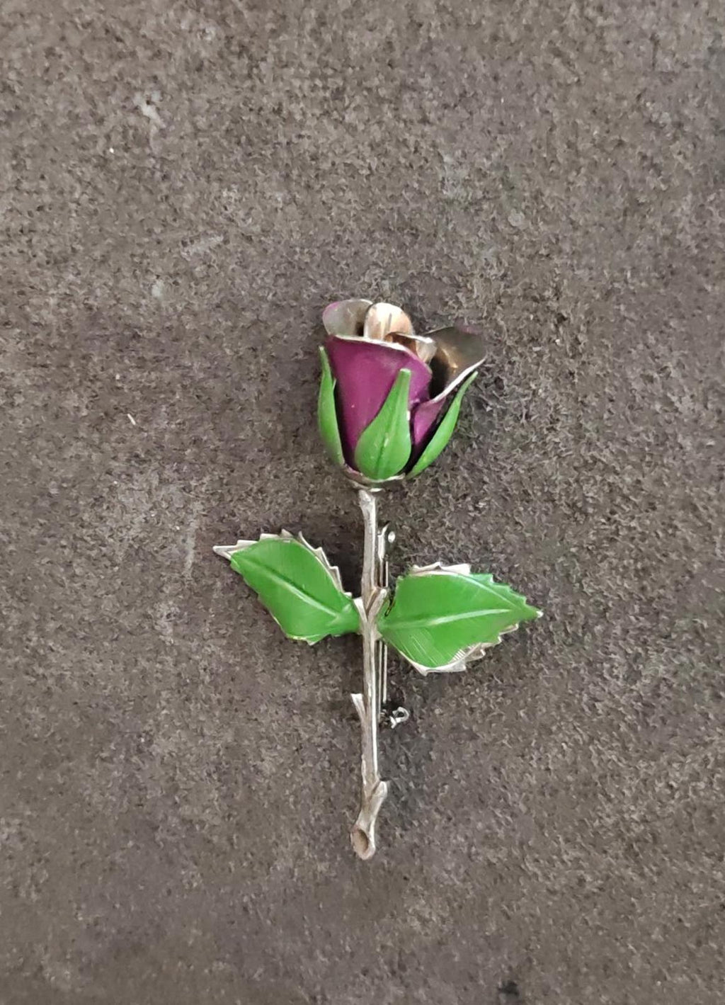 Rose brooch with purple enamel center, green leaves, and silver-toned pin back