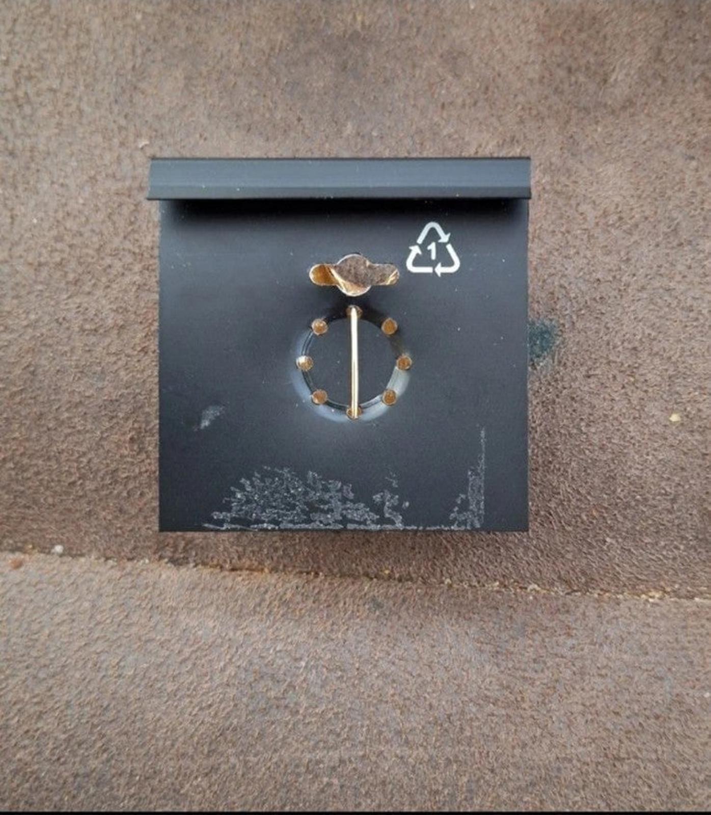 Enamel pin back with circular clasp and recycling symbol on backing card