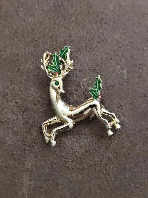 Gold-tone reindeer brooch with green enamel holly, standing pose with legs extended