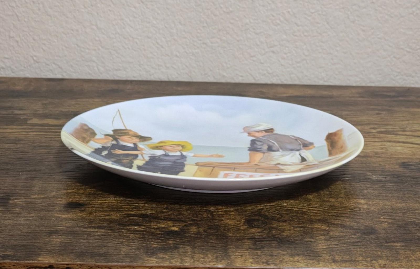 Blue ceramic decorative plate shown from the side with printed fish market artwork
