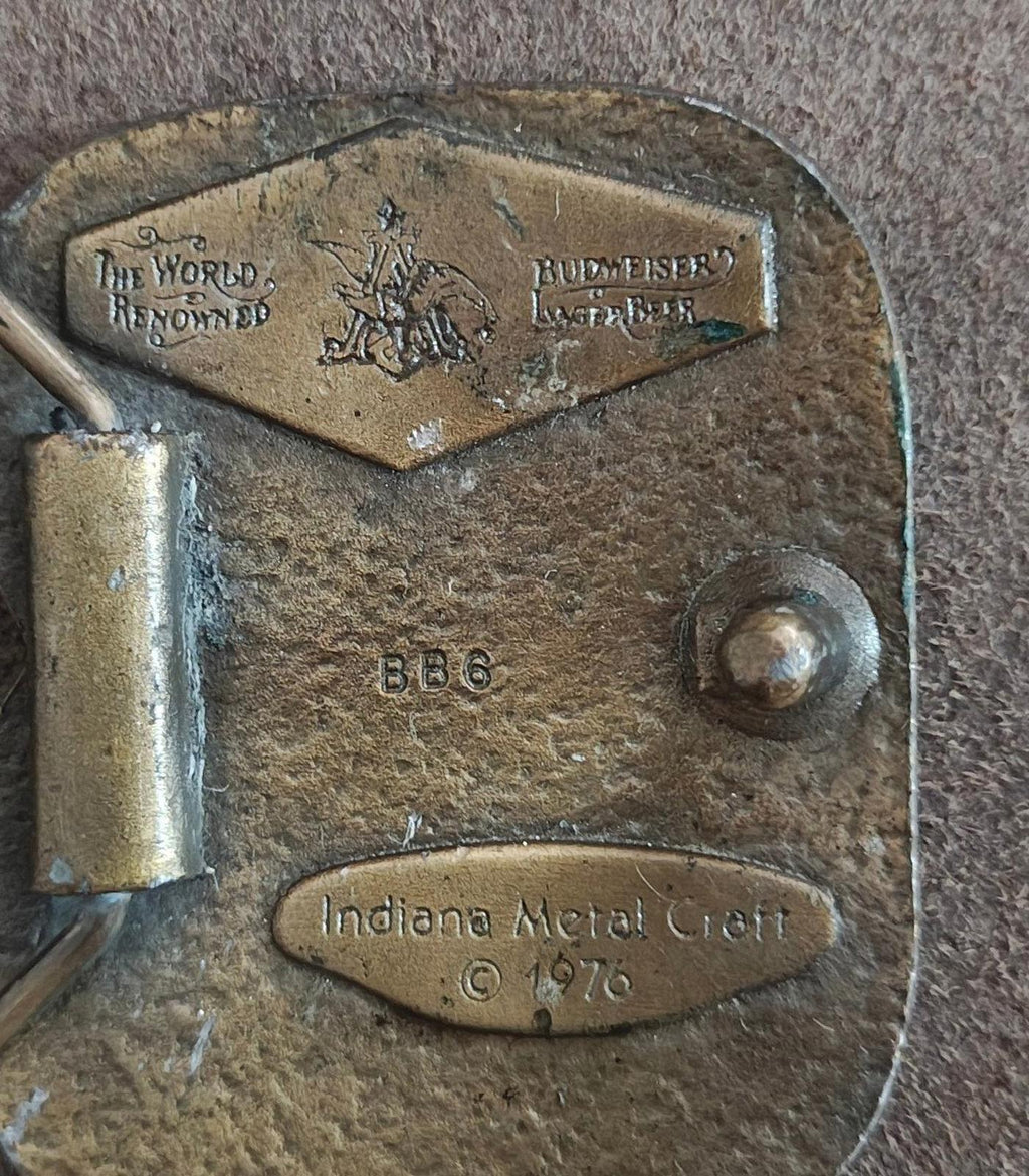Vintage brass belt buckle back close-up showing "Indiana Metal Craft" and "© 1976" text.