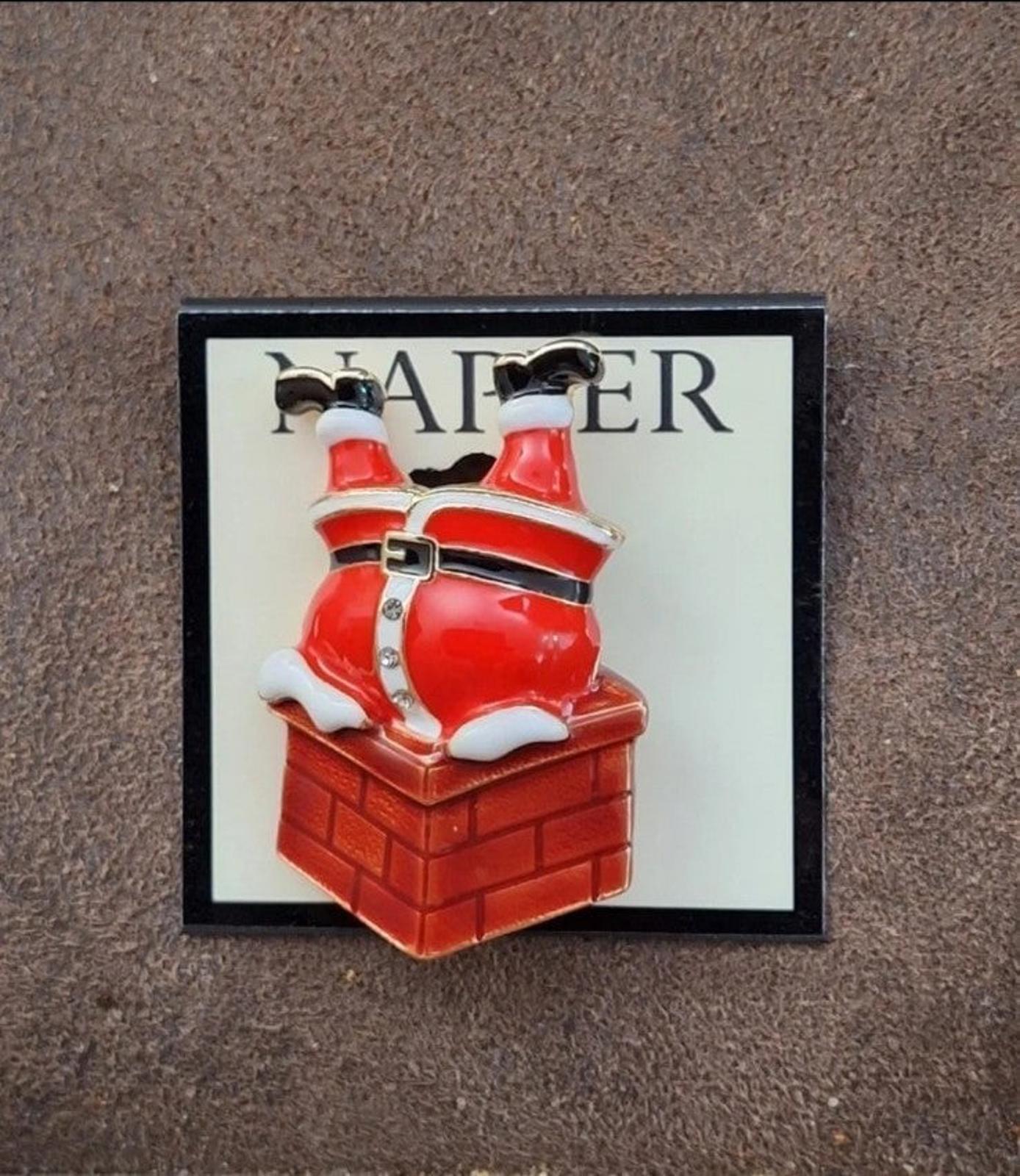 Red enamel Santa climbing down chimney pin on card, slightly angled view