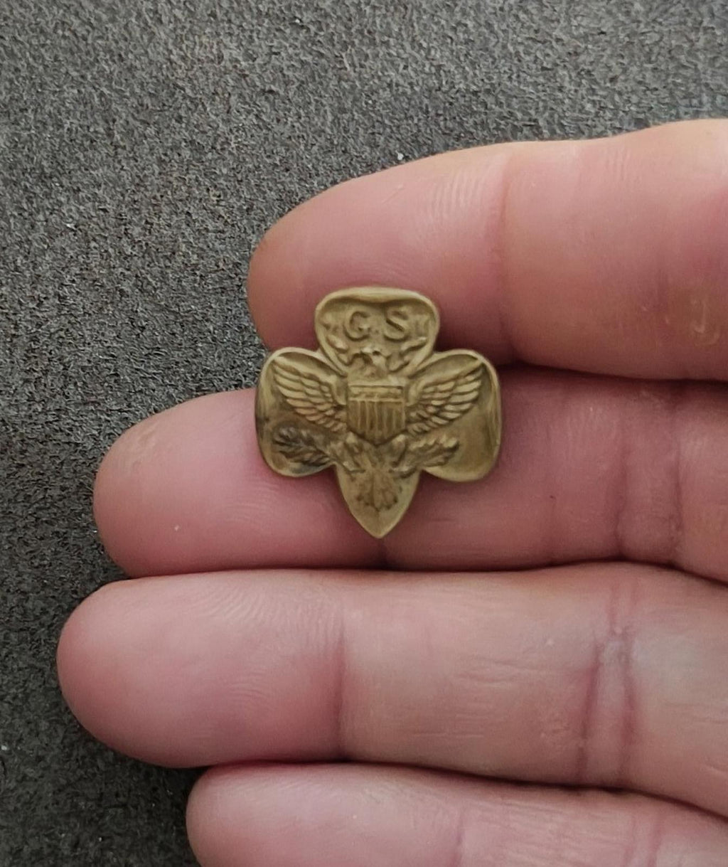 Gold-tone Girl Scout eagle brooch pin with GS crest and shield, small view on hand