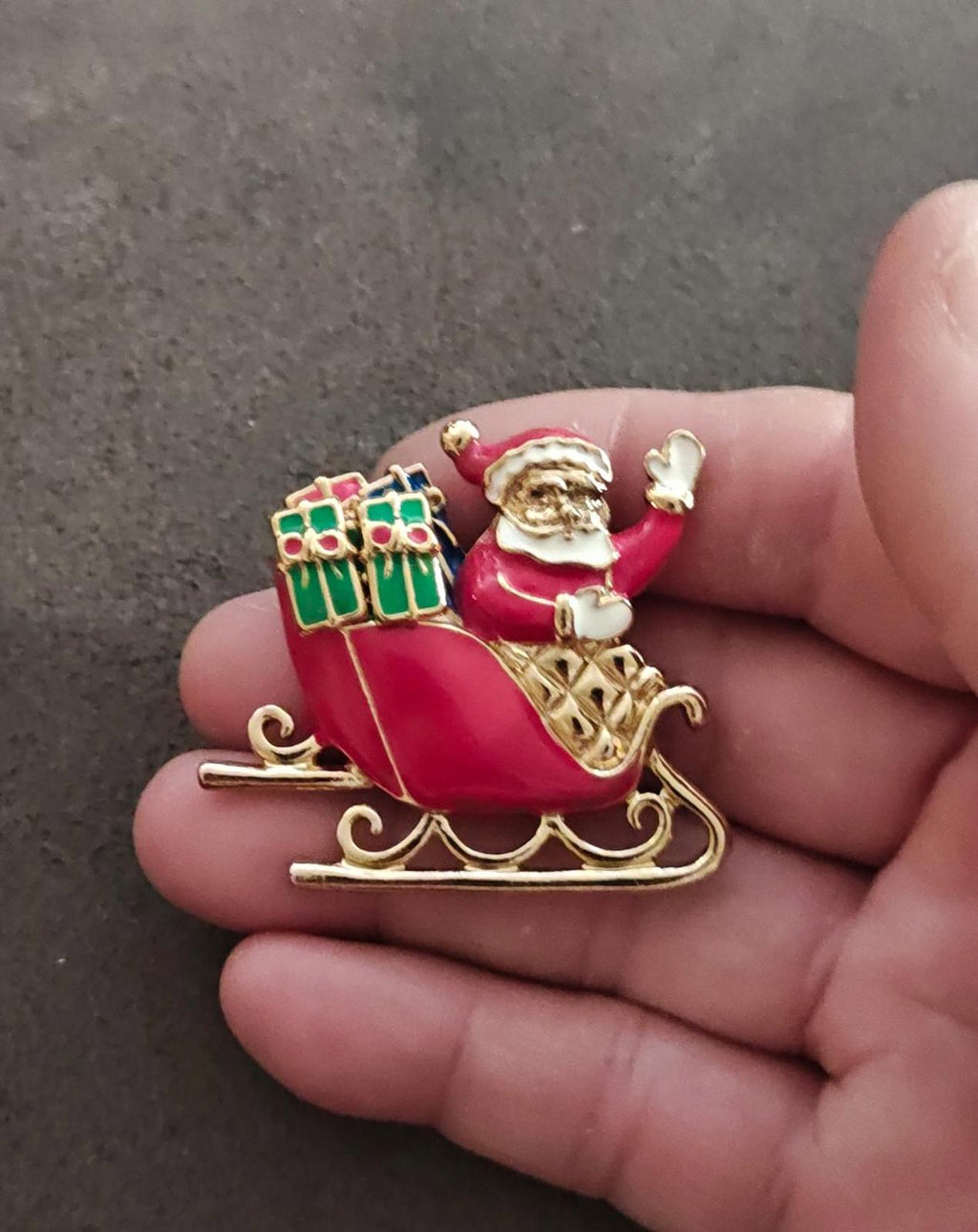 Red Santa sleigh brooch with gold-tone trim, green gift accents, and white beard
