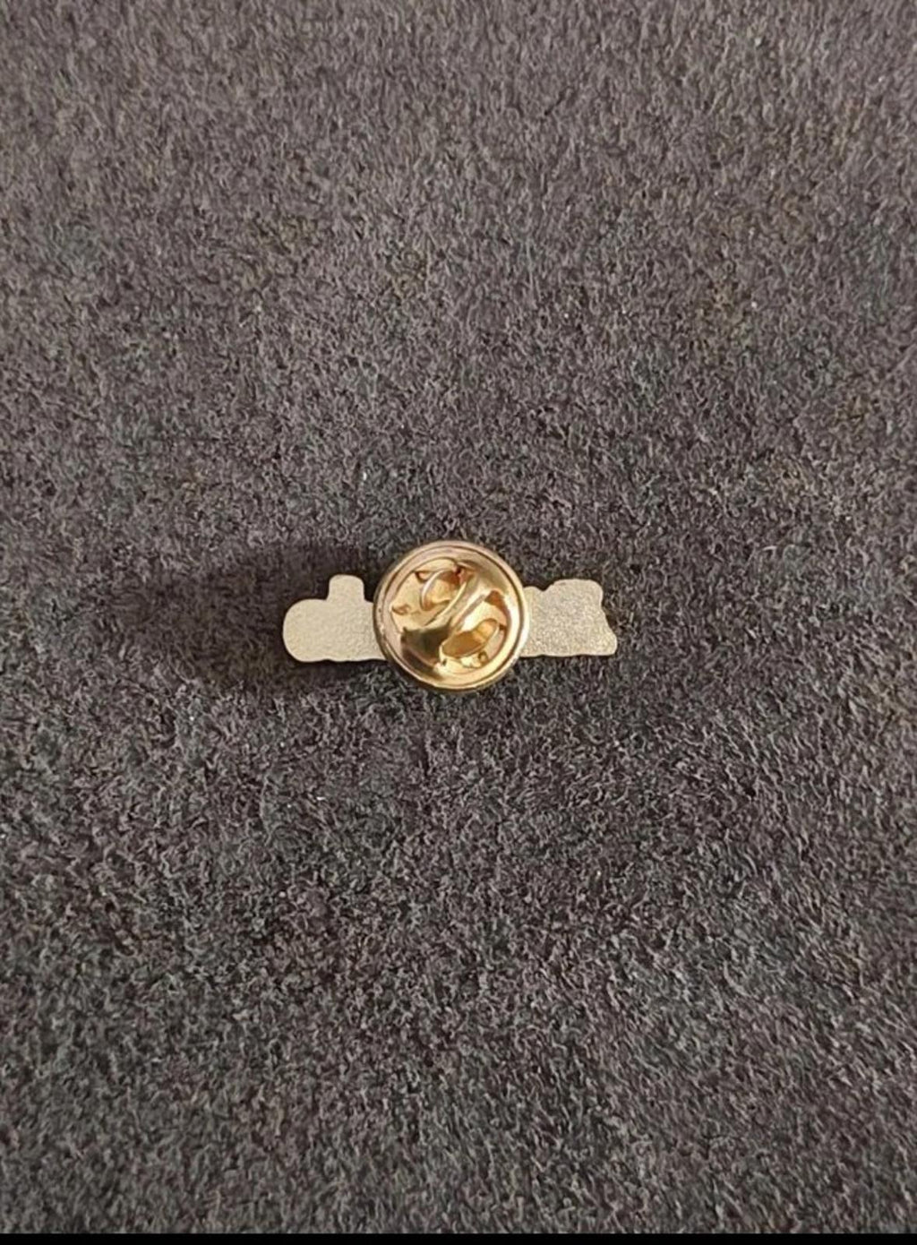 Gold tone lapel pin backing with round clutch and bar; "Attitude" front visible